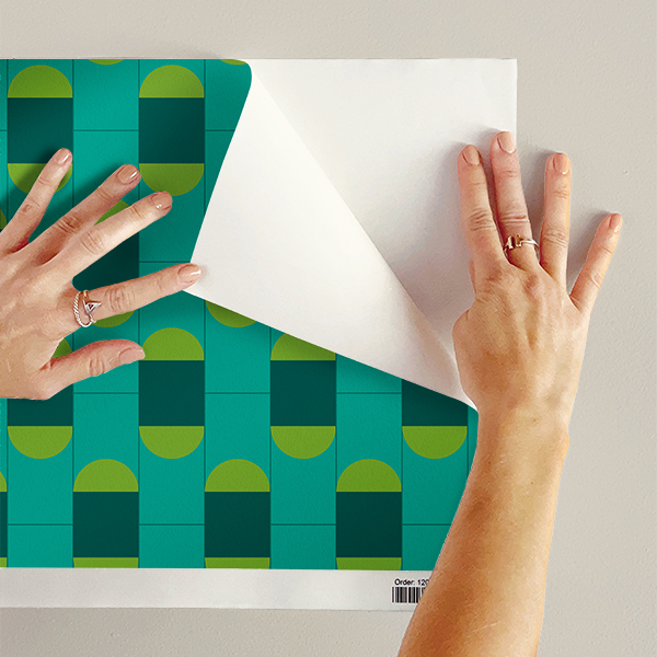 The artwork features a repeating geometric pattern of symmetrical shapes resembling elongated, curved diamonds or petals in various shades of blue and green. Each shape is split vertically with one half filled with a light blue and the other half filled with green or darker blue. The background is a light, almost pastel blue, which provides a soft yet vibrant backdrop. One of the blue shapes near the upper left contains a white starburst element, adding a focal point of brightness to the composition. The overall design conveys a modern, mid-century aesthetic with clean lines and harmonious color contrasts.